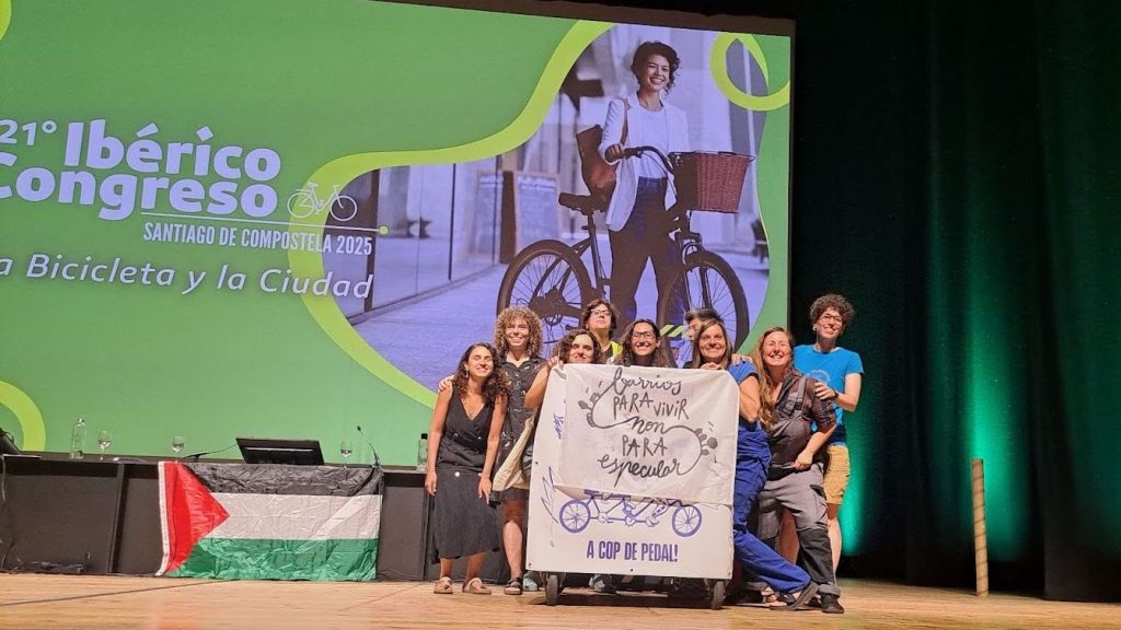 Grupo de mulheres no palco do congresso ergue um cartaz